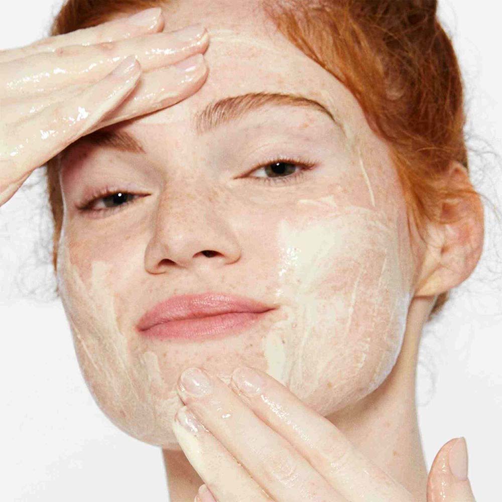 woman cleansing face with daily milkfoliant