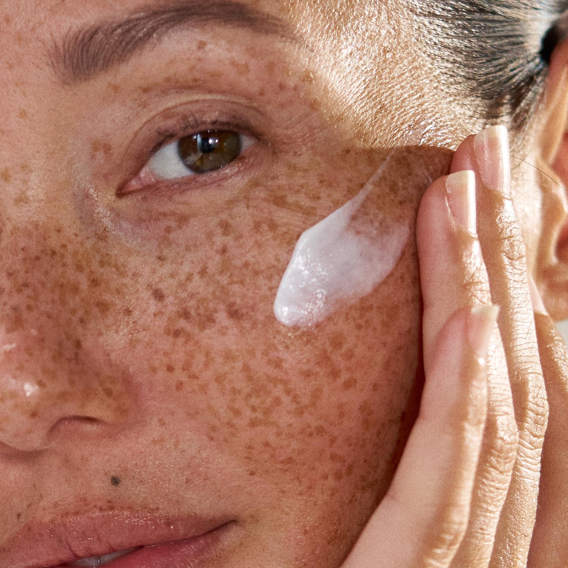 model applying moisturizer on face