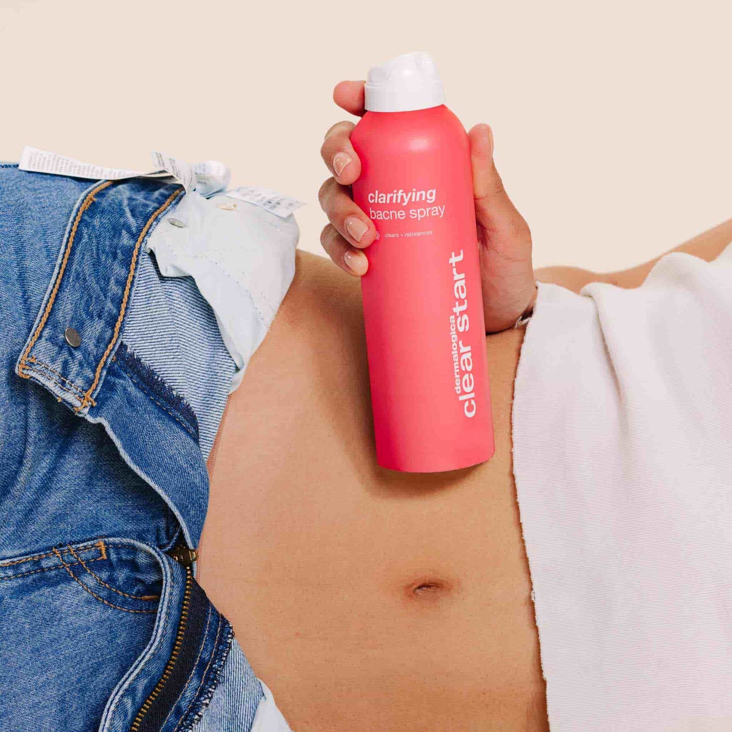 Model holding Clarifying Bacne Spray against stomach