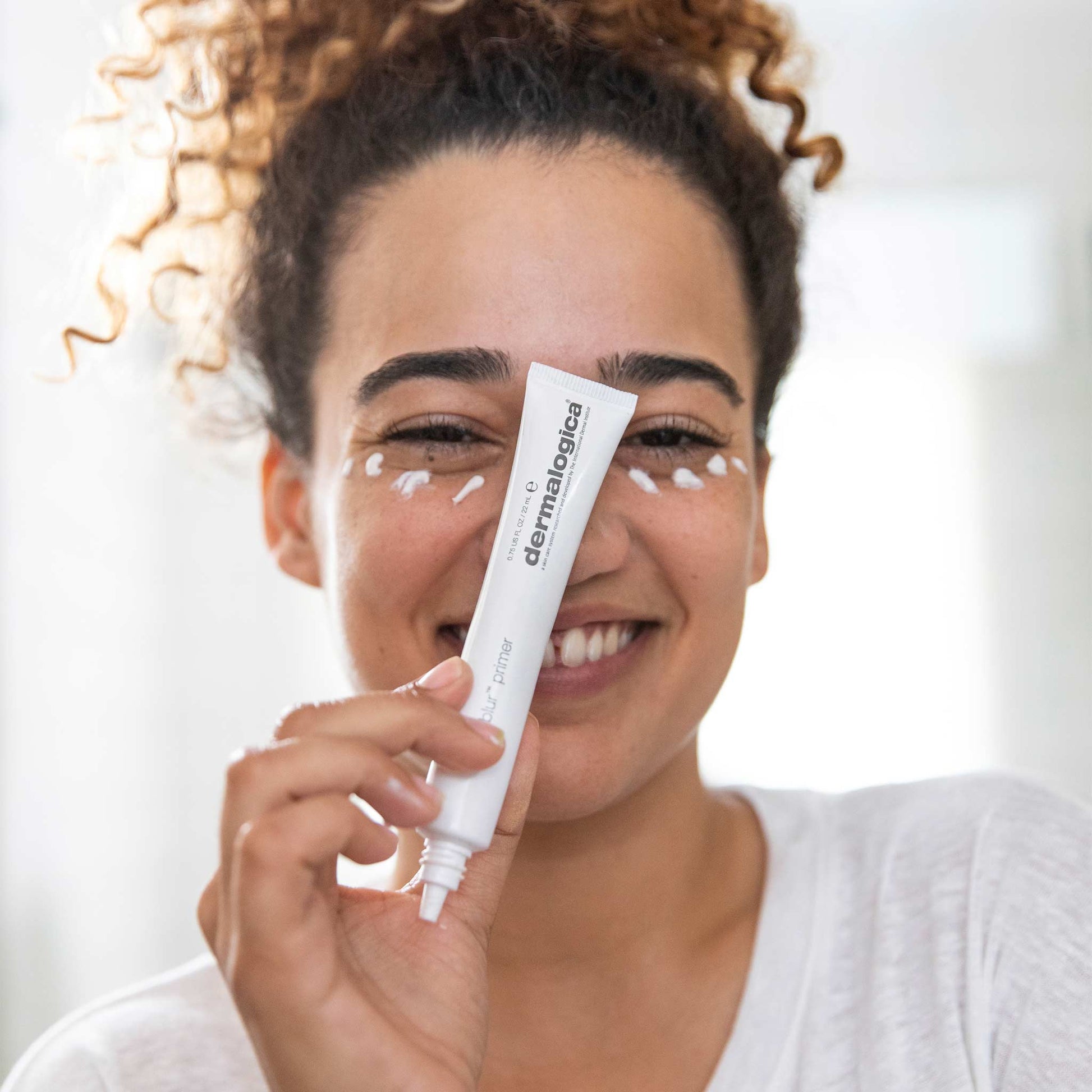 woman holding hydrablur primer with product on face