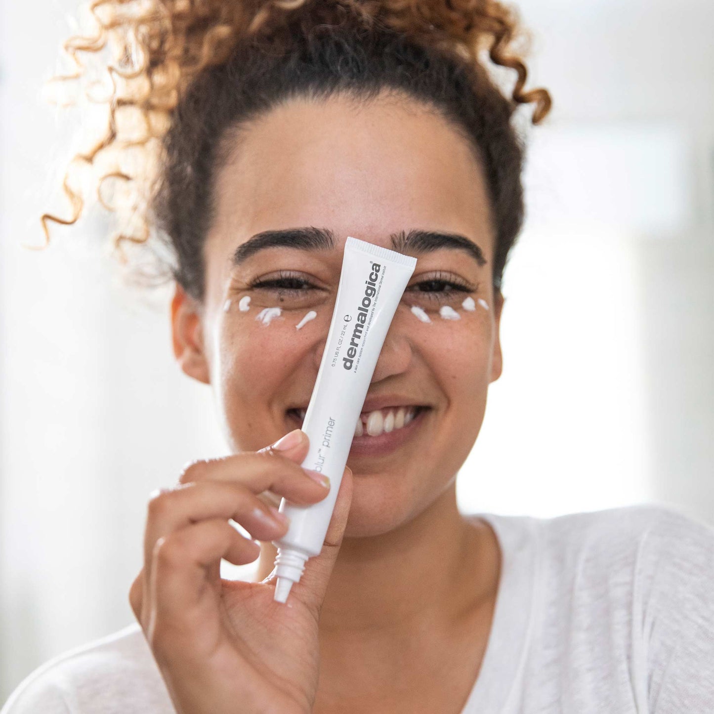 woman holding hydrablur primer with product on face 