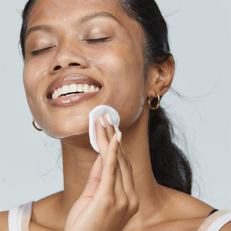 woman wiping off ultracalming cleanser with cotton round